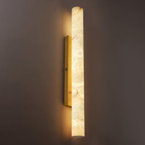 A long, elegant brass and alabaster wall sconce casting a soft glow in a modern hallway.